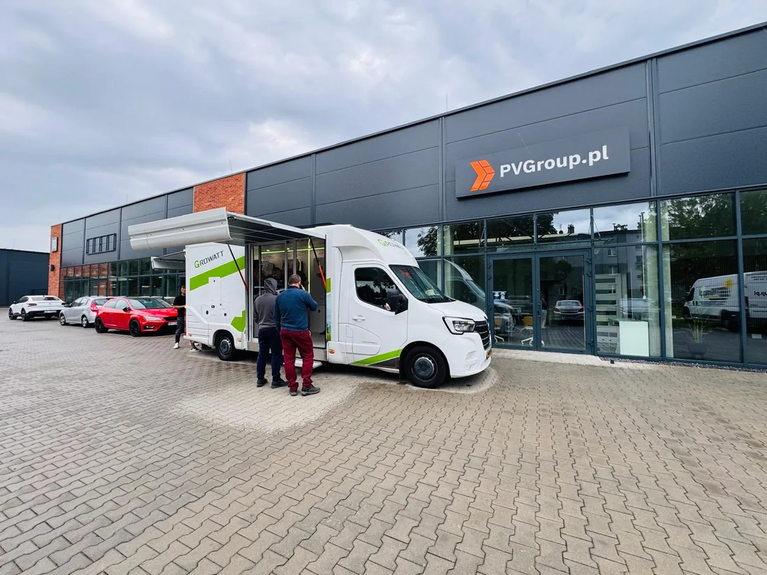 Odwiedzający oglądają falowniki i magazyny energii Growatt we wnętrzu mobilnego centrum